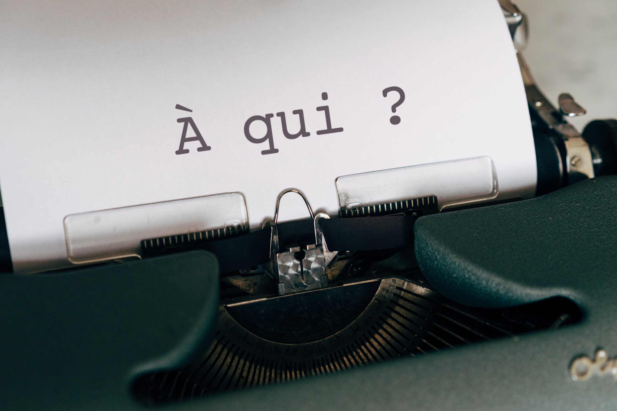 Machine à écrire avec sur le papier écrit "À qui ?"